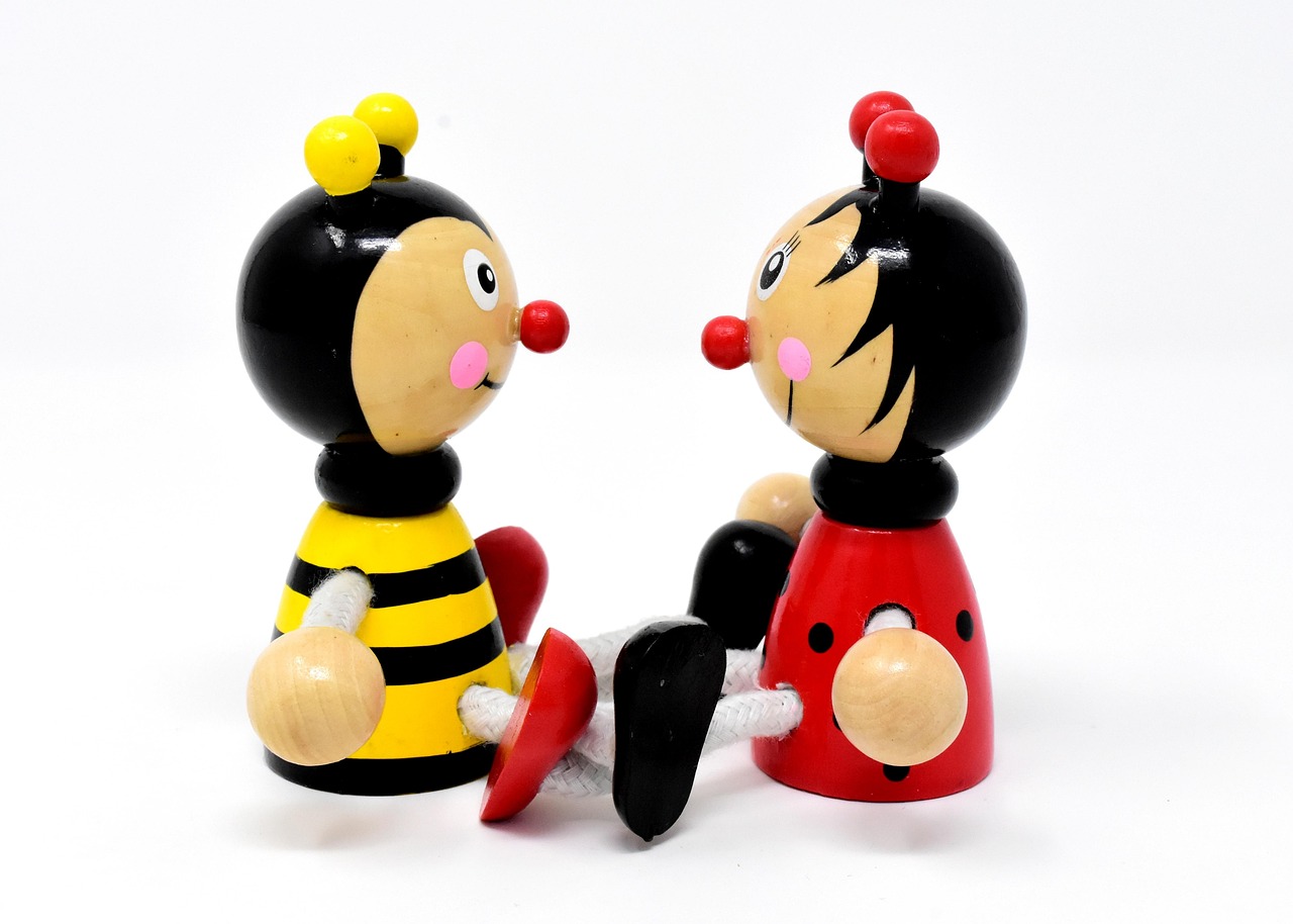 Zwei Holzfiguren, eine Biene und ein Marienkäfer, schauen sich an